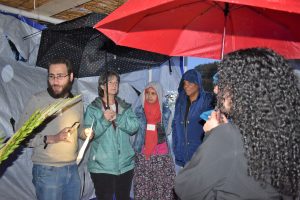 Students inside sukkah with umbrellas