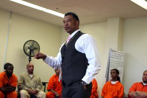 Picture of African American man talking to a group of prisoners